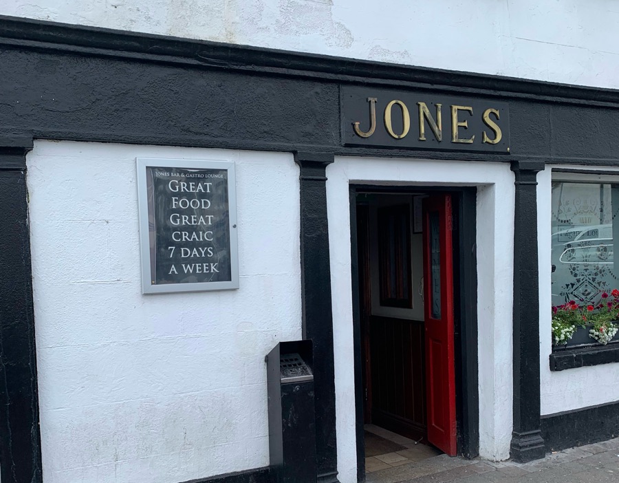 The Jones’ shopfront: gilt JONES lettering on a black fascia, an open red door and a chalkboard reading Great Food, Great Craic, 7 Days a Week