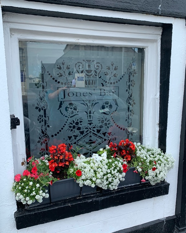 Etched glass in the front window spelling Jones’ Bar, above a box of red and white flowers